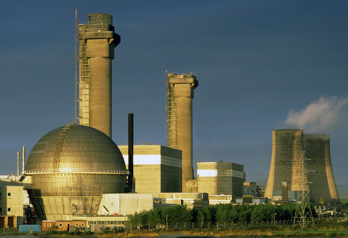 Nuclear & Decommissioning Industrial power plant with cooling towers and large spherical structures under a blue sky.